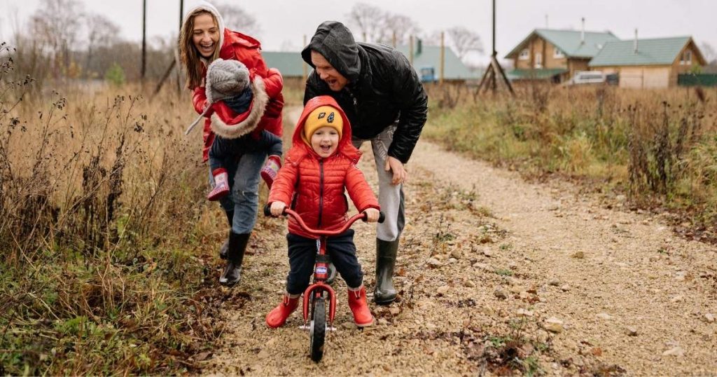 Mum Dad and two children playing outside with small bike